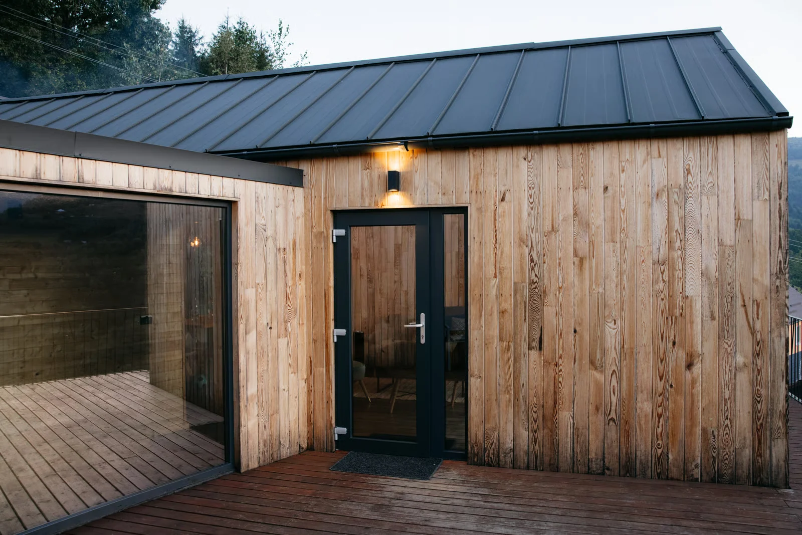 Photo. Timber-clad exterior with a standing-seam roof, dusk